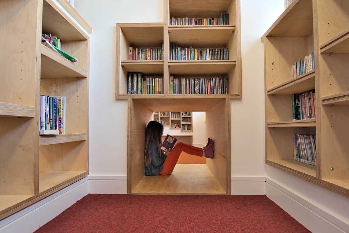 Beaudesert Park School Library child reading in a plywood reading nook surrounded by bookshelves